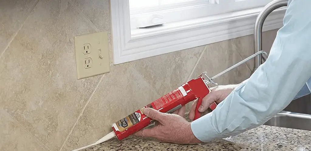 Handyman applying caulk along a kitchen backsplash and countertop seam in Glendale, AZ