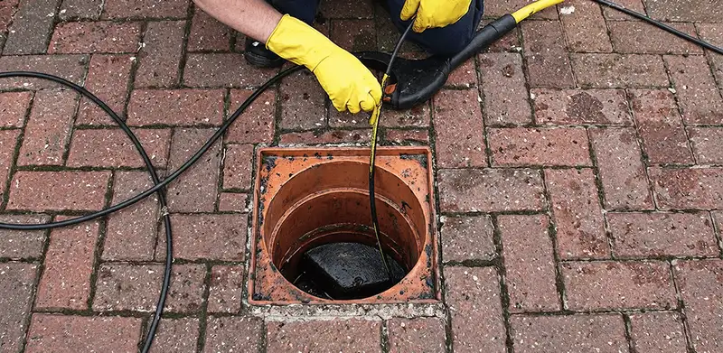 Drain cleaning technician using a drain snake to clear a clogged drain in Glendale, AZ