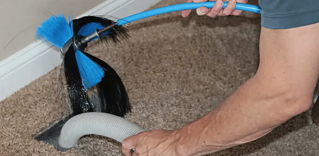Dryer vent cleaning technician brushing lint from a vent line in Glendale, AZ