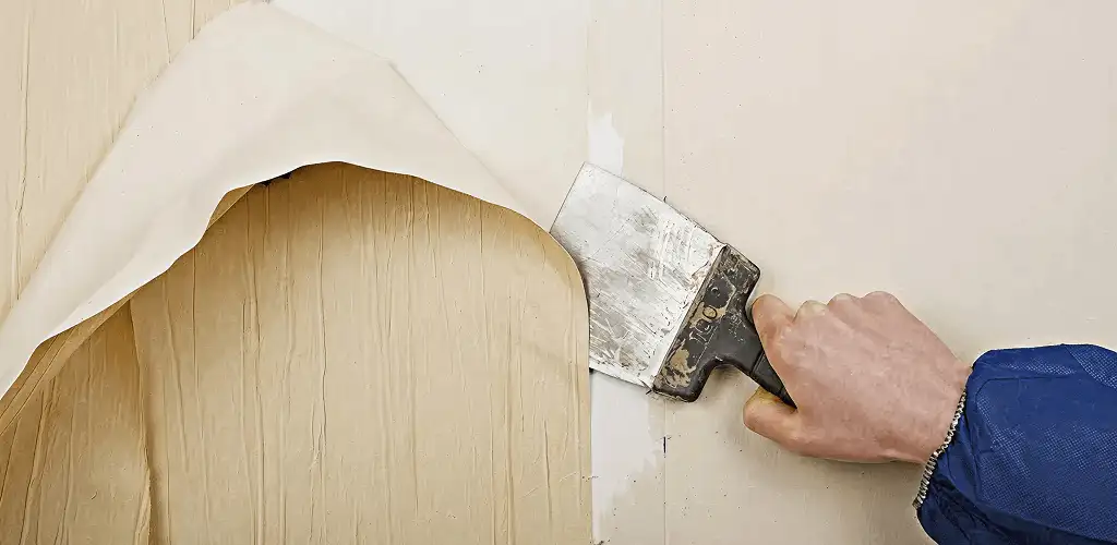 Handyman removing wallpaper with a scraper for wall preparation in Glendale, AZ