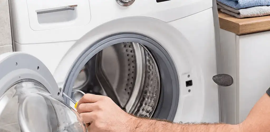 Handyman repairing a front-load washing machine and inspecting the drum in Glendale, AZ
