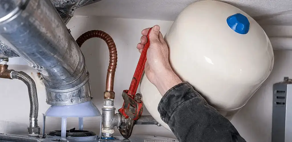 Water heater repair technician tightening plumbing connections near a tank unit in Glendale, AZ